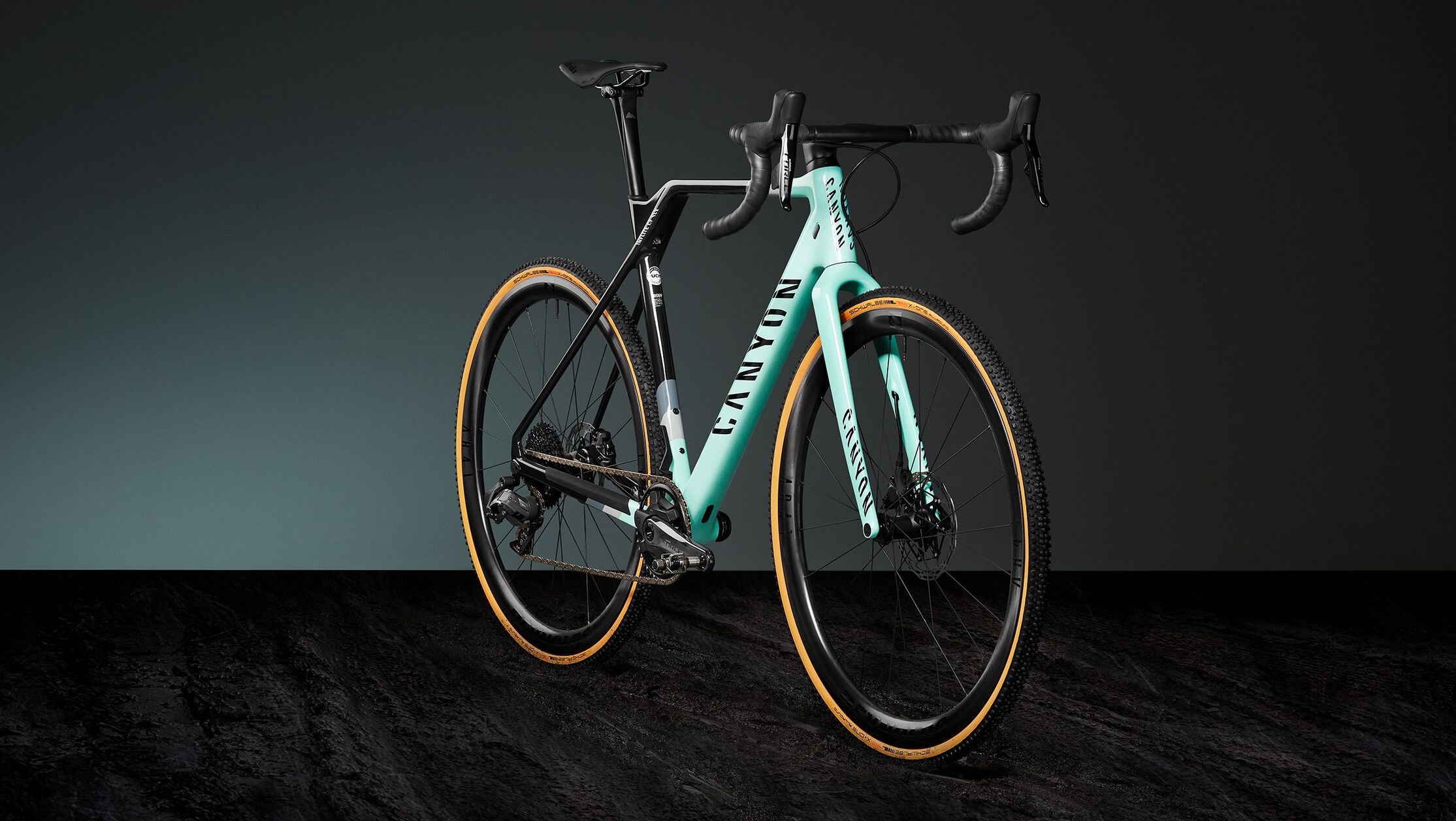 Canyon Inflite cyclocross bike with teal and black frame, integrated cockpit, and knobby tires, designed for aggressive off-road and race conditions.