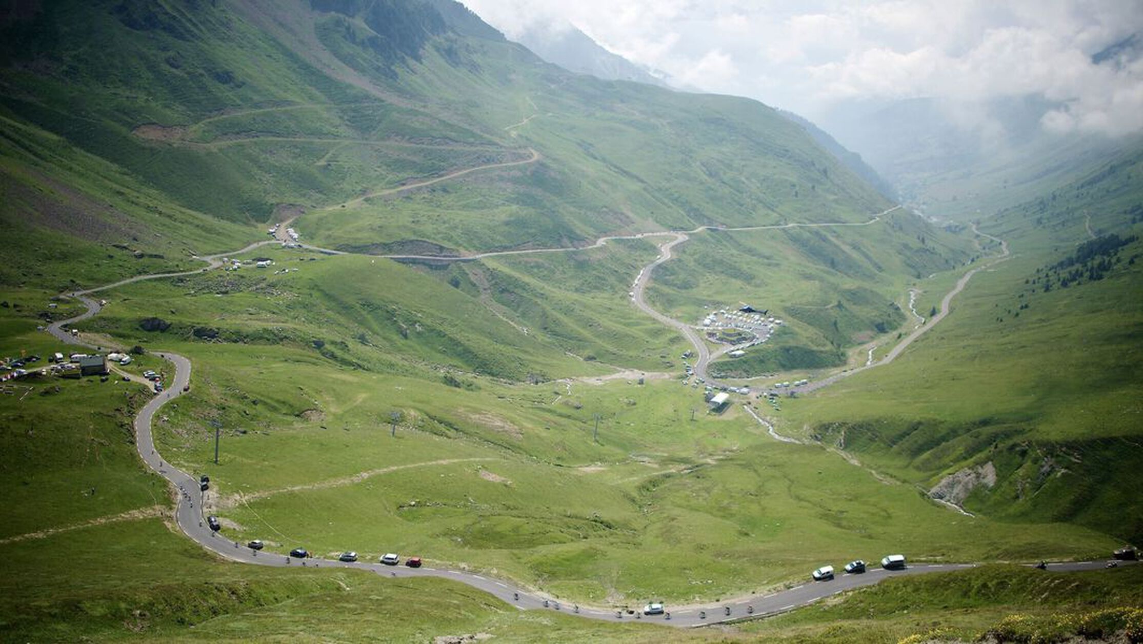 Aerial view of Tour de France 2024 on the Tourmalet stage, showing winding road and scenic mountain hills