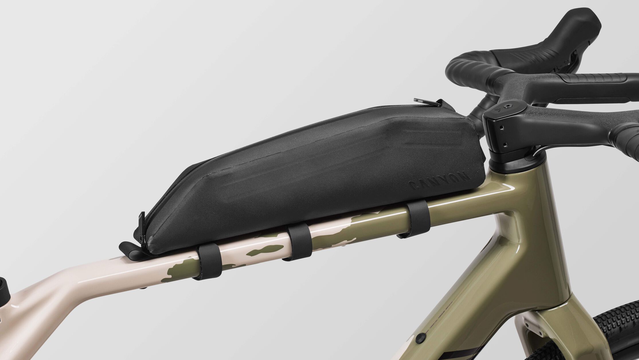 Canyon Grizl CF 7 ESC 砾石车的特写，显示其装有一个上管包，非常适合需要在长途骑行中携带补给、工具或装备的初学者。