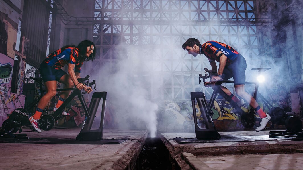Two riders face each other on their turbo trainers in a battle on Zwift