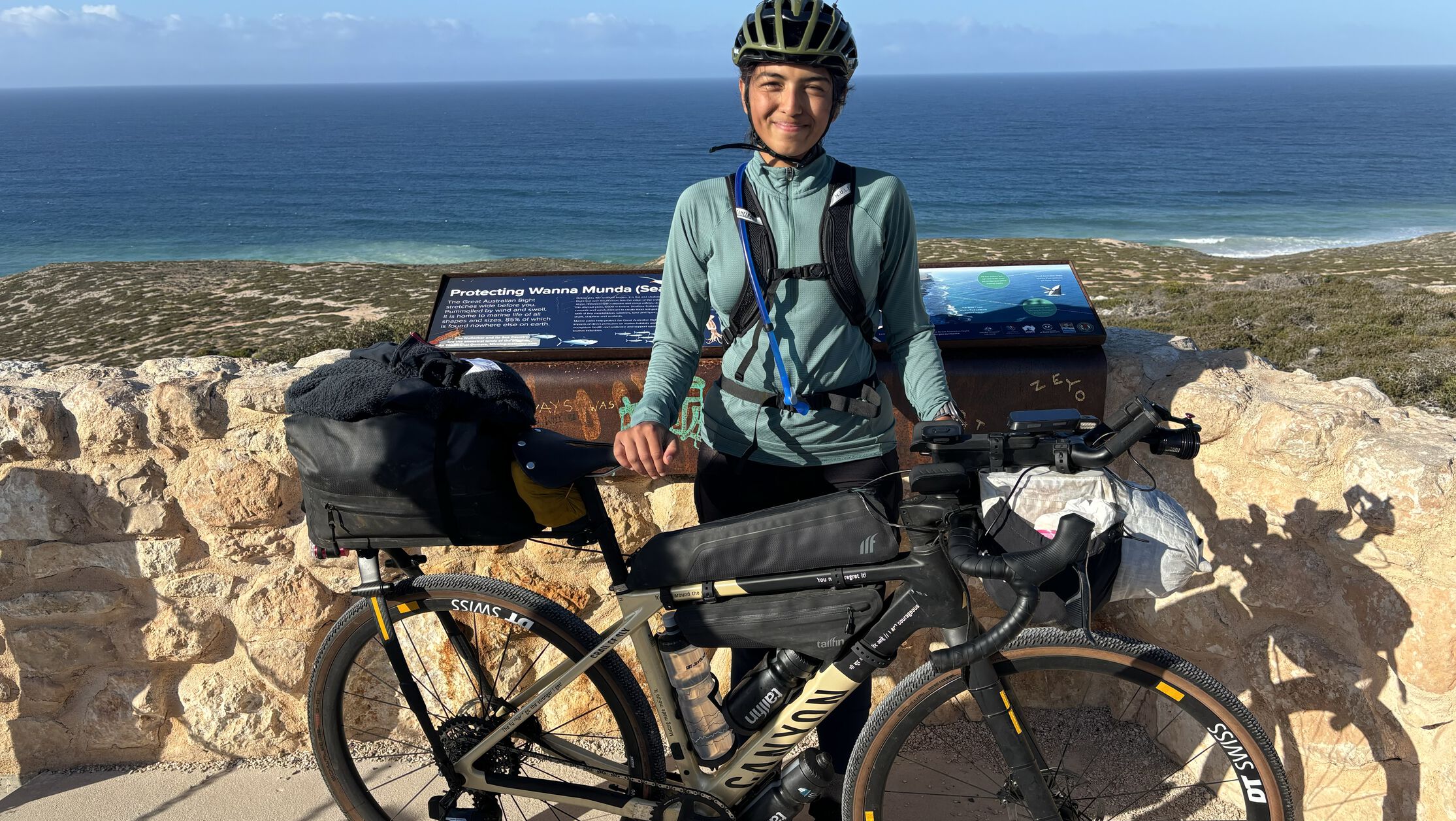 Vedangi Kulkarni with a fully loaded Canyon bikepacking setup near the coast, sharing tips on how to bikepack on a budget and travel smart