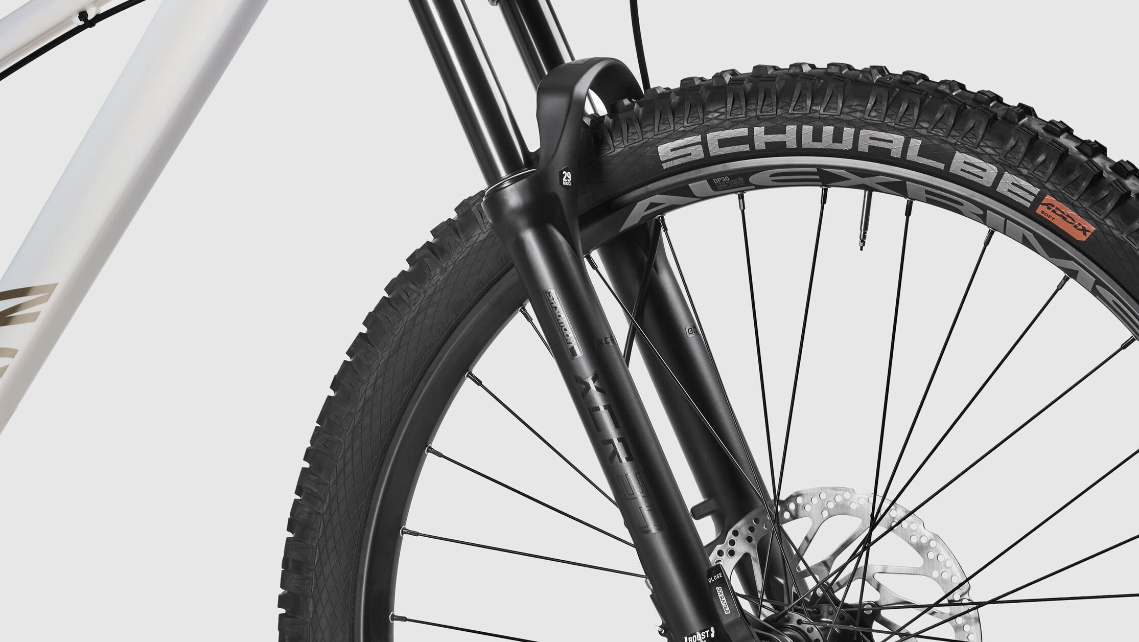 Close-up of the front suspension fork on a Canyon Stoic hardtail mountain bike, featuring Schwalbe tires and powerful disc brakes, optimized for versatile trail performance.