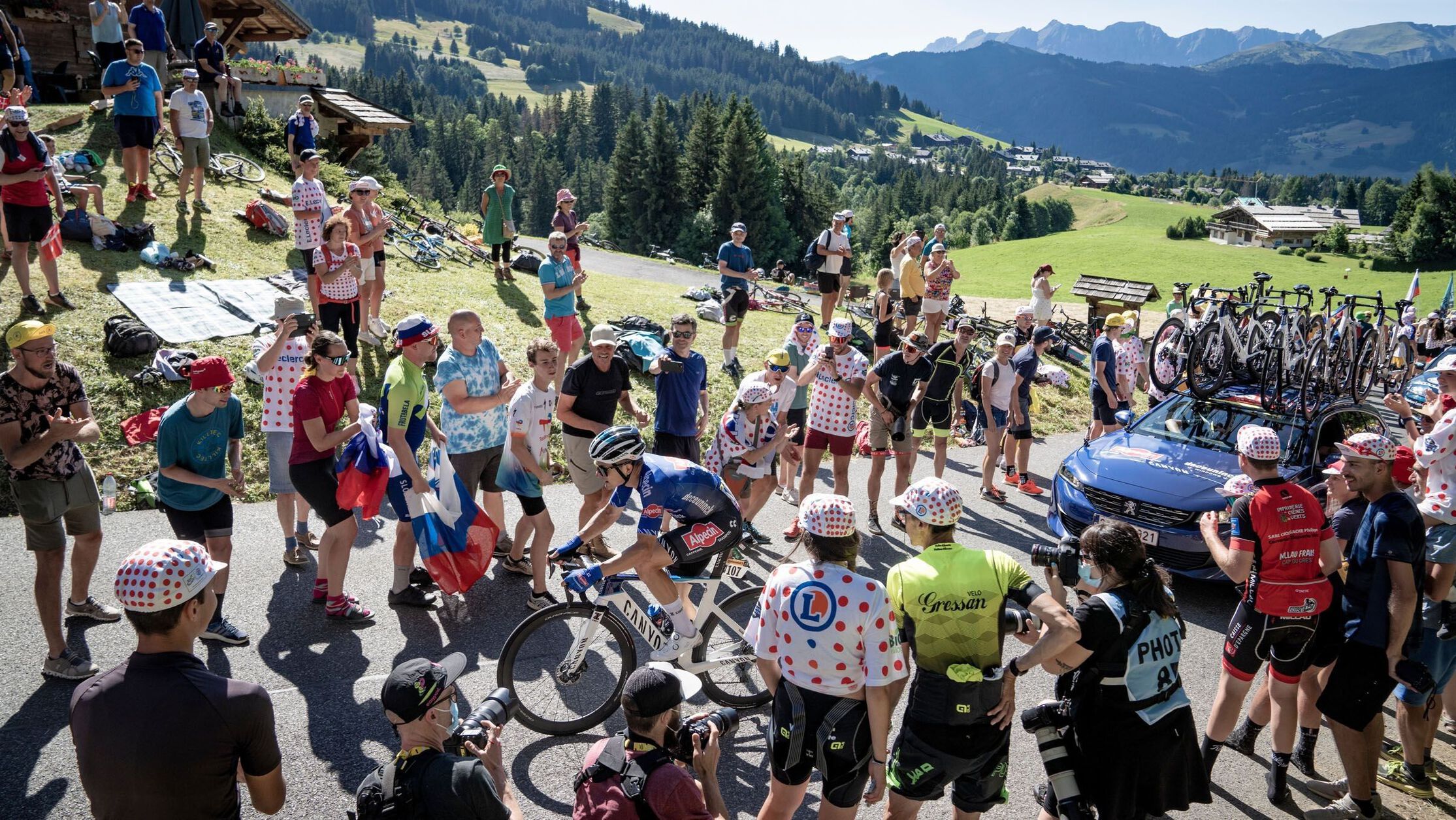 Alpecin team rider on a Canyon bike climbs a hill at Tour de France 2024, cheered on by fans lining the roadside 